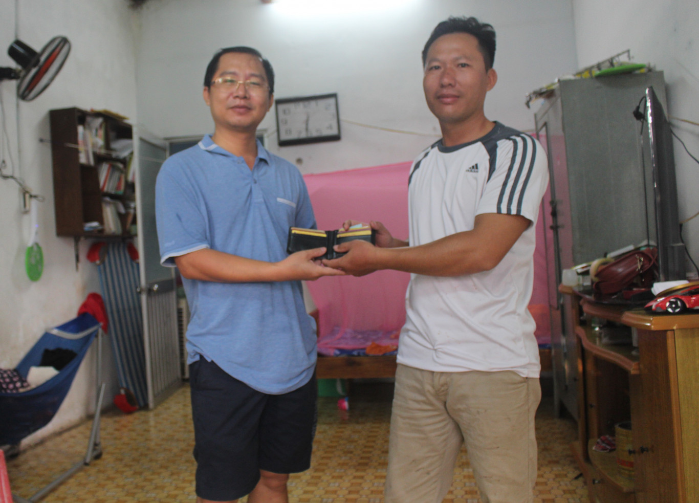 Anh Lê Văn Hiếu (người mặc ái mầu sọc đen trắng) trao trả lại cái bóp cho anh Nguyễn Thành Tâm